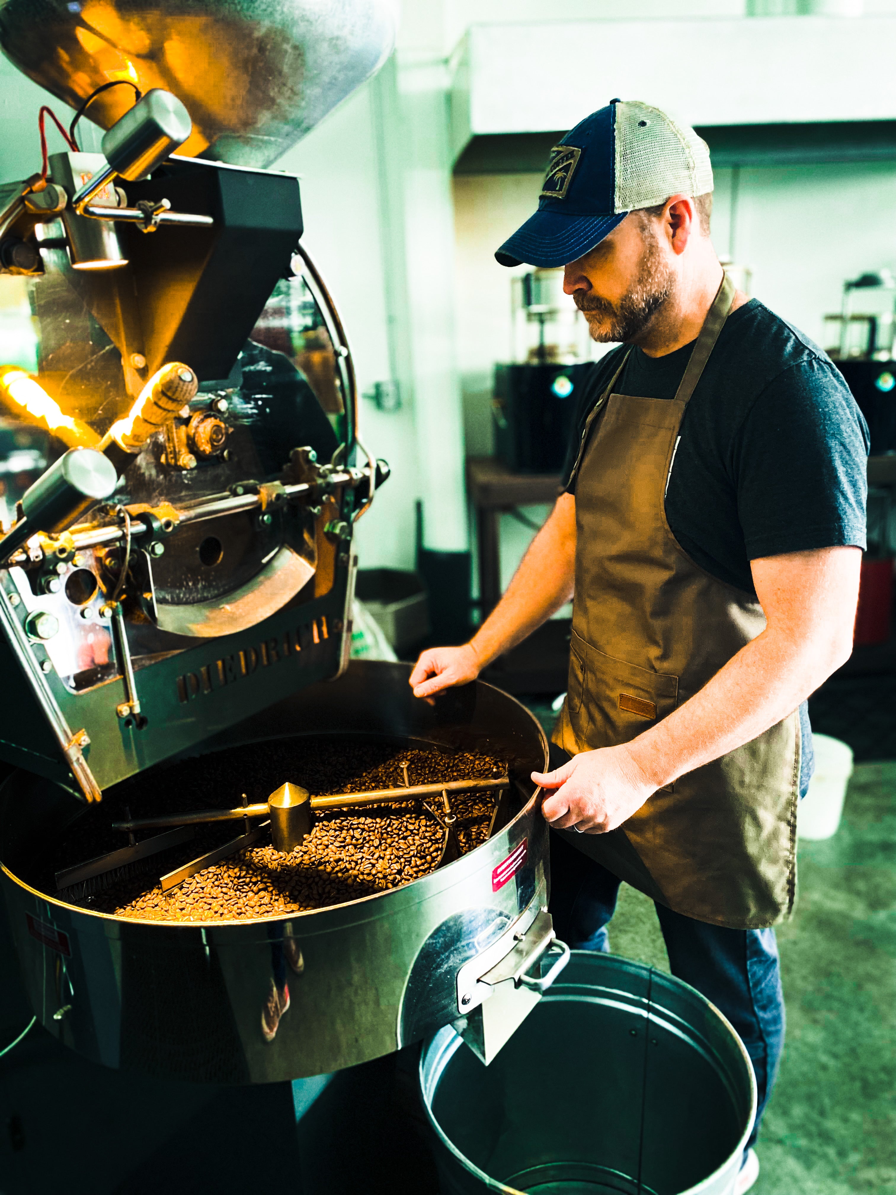 Man operating a coffee roasting machine in a coffee shop.