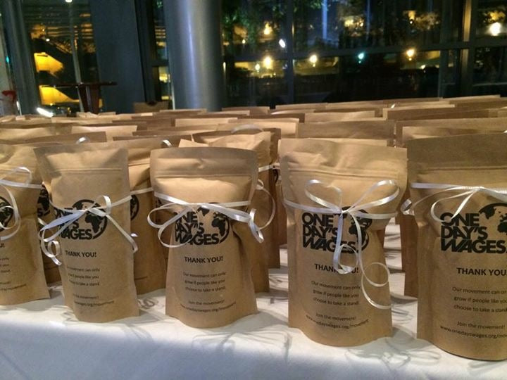 Row of kraft coffee bags with white ribbons and printed text on a white surface.